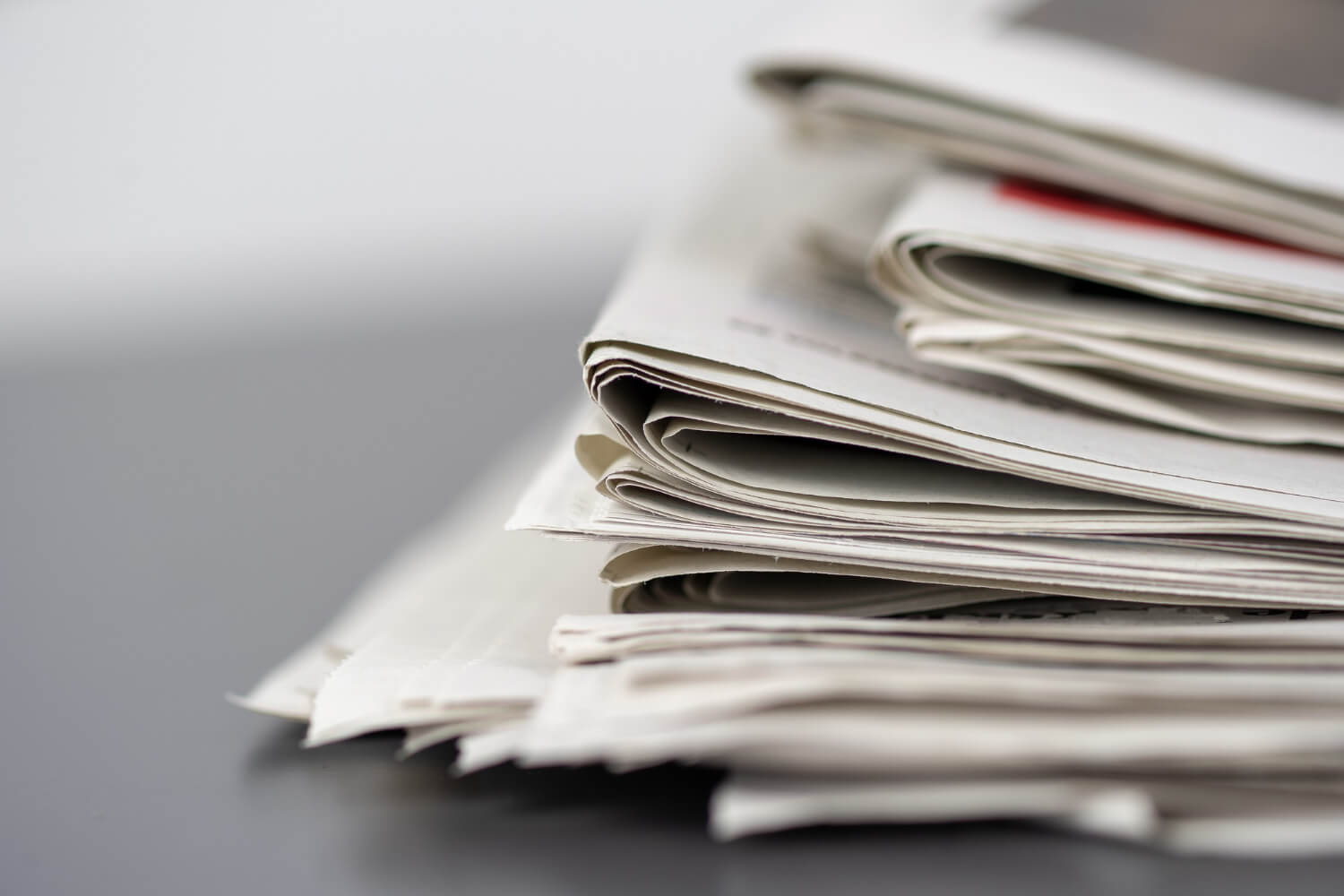 closeup-shot-several-newspapers-stacked-top-each-other